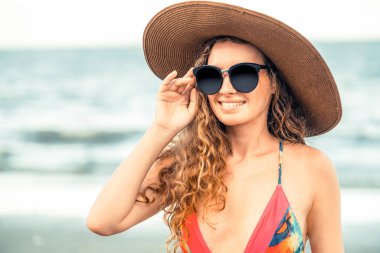 Tatil seyahat etmek tatil için yaz aylarında tropikal plaj keyfi yerinde mayo giyen mutlu genç kadın.