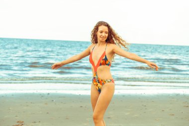 Tatil seyahat etmek tatil için yaz aylarında tropikal plaj keyfi yerinde mayo giyen mutlu genç kadın.