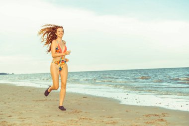 Çekici kadın runner yaz aylarında tropikal Kum Plajı üzerinde çalışır. Sağlıklı yaşam tarzı ve koşma spor kavramı.