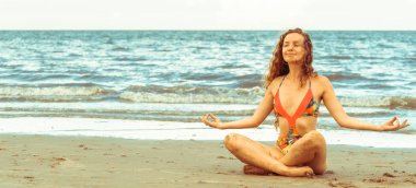 Genç kadın pratik yoga poz sahilde yaz. Sağlıklı yaşam tarzı ve meditasyon.