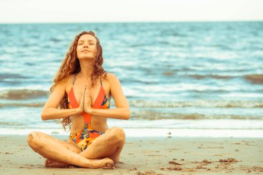 Genç kadın pratik yoga poz sahilde yaz. Sağlıklı yaşam tarzı ve meditasyon.