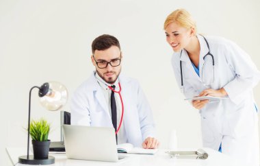 Doktor hastane ofis dizüstü bilgisayar masanın üzerinde başka bir doktor hasta sağlık hakkında tartışma ile çalışma.