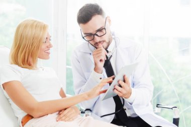 Erkek doktor ve Bayan hasta sağlık veri kaydı için tablet bilgisayar bakıyor. Sağlık ve tıbbi hizmet.