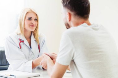 Kadın doktor hastane office odasında erkek hasta ile karşılıklı yapıyor. Sağlık ve Medikal hizmet meslekleri.