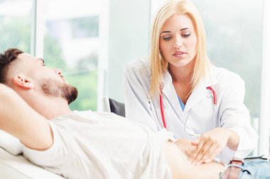 Kadın doktor konuşuyor ve erkek hasta hastane ofisinde inceleyerek. Sağlık ve tıbbi hizmet.