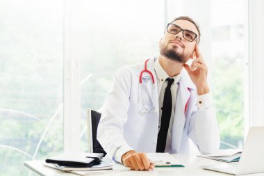 Hastanede ofis masasında çalışırken düşünme doktor. Tıbbi ve sağlık kavramı.