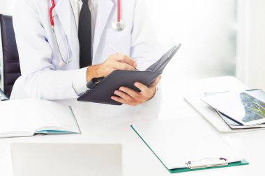 Doktor ofisinde hastanede bir kitap üzerine not yazarken okuma. Tıbbi ve sağlık kavramı.