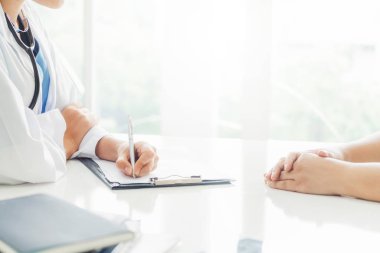 Kadın doktor görüşmeler yazarken bayan hasta için hastanın sağlık kaydının hastane ofiste. Sağlık ve tıbbi hizmet.