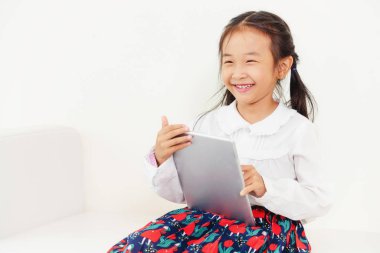 Tablet bilgisayar ile beyaz arka plan üzerinde küçük mutlu çocuk. Çocukluk yaşam tarzı.