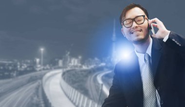 Genç işadamı istimal hareket eden telefon ile modern şehir binaları arka plan.