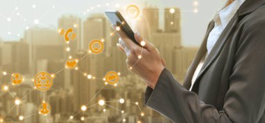 Cep telefonu ile modern şehir binaları arka plan kullanarak genç iş kadını. Gelecekteki telekomünikasyon teknolojisi ve internet şeyler (çok) kavramının.
