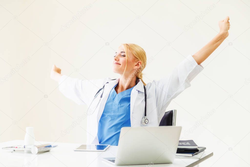 Relaxed woman doctor takes deep breath while working on medical report at office table. Stress relief and control concept.