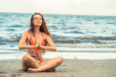 Genç kadın pratik yoga poz sahilde yaz. Sağlıklı yaşam tarzı ve meditasyon.