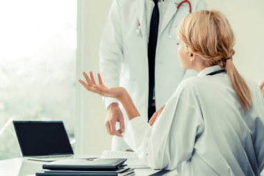 Genç kadın doktor hastane ofisindeki masanın ayakta başka bir erkek doktor ile konuşurken konuşmayı. Tıbbi sağlık profesyonel takım kavramı.