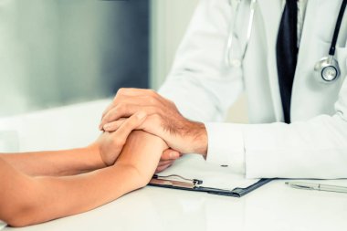 Erkek doktor hastane ofiste bayan hasta hasta ellerini tutarak yatıştırır. Sağlık ve tıbbi hizmet.