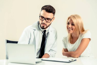 Erkek doktor hastane ofiste bayan hasta masada dizüstü bilgisayarda hastalar sağlık verilere bakarken konuştuğu. Sağlık ve tıbbi hizmet.