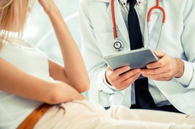 Erkek doktor konuşuyor ve Bayan hasta hastane ofisinde inceleyerek. Sağlık ve tıbbi hizmet.