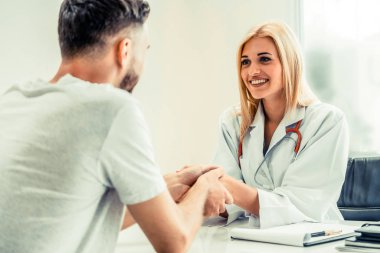 Kadın doktor hastane office odasında erkek hasta ile karşılıklı yapıyor. Sağlık ve Medikal hizmet meslekleri.