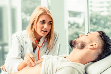 Kadın doktor konuşuyor ve erkek hasta hastane ofisinde inceleyerek. Sağlık ve tıbbi hizmet.