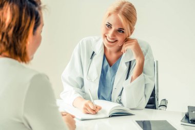 Kadın doktor konuşuyor ve Bayan hasta hastane ofisinde inceleyerek. Sağlık ve tıbbi hizmet.