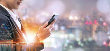 Cep telefonu ile modern şehir binaları arka plan kullanarak genç iş kadını. Gelecekteki telekomünikasyon teknolojisi ve internet şeyler (çok) kavramının.