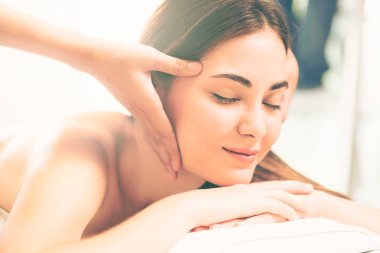 Lüks bir spa merkezinde masaj terapisti tarafından yüz masajı ve spa tedavisi için kaplıcaya uzanmış rahat bir kadın. Sağlık, stres atma ve gençleştirme kavramı.