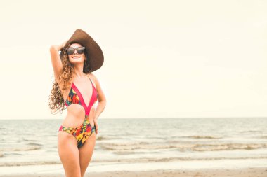Tatil seyahat etmek tatil için yaz aylarında tropikal plaj keyfi yerinde mayo giyen mutlu genç kadın.