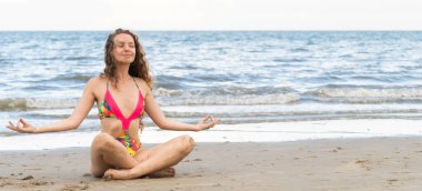 Genç kadın pratik yoga poz sahilde yaz. Sağlıklı yaşam tarzı ve meditasyon.