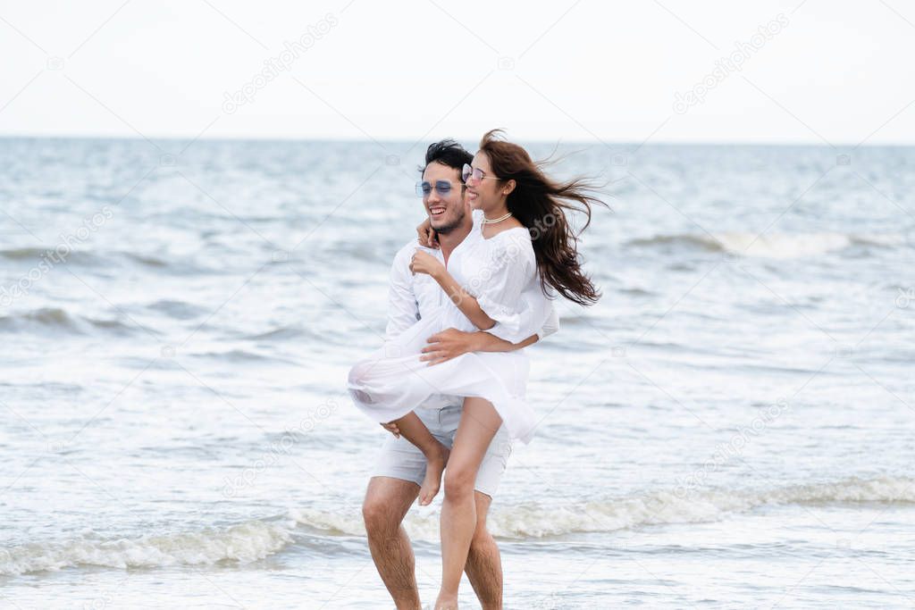 Happy couple going honeymoon travel on tropical sand beach in summer.