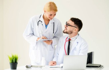 Doktor hastane ofis dizüstü bilgisayar masanın üzerinde başka bir doktor hasta sağlık hakkında tartışma ile çalışma.