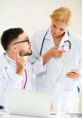 Doktor hastane ofis dizüstü bilgisayar masanın üzerinde başka bir doktor hasta sağlık hakkında tartışma ile çalışma.