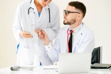 Doktor hastane ofis dizüstü bilgisayar masanın üzerinde başka bir doktor hasta sağlık hakkında tartışma ile çalışma.