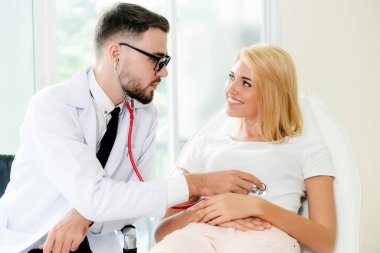 Erkek doktor konuşuyor ve Bayan hasta hastane ofisinde inceleyerek. Sağlık ve tıbbi hizmet.