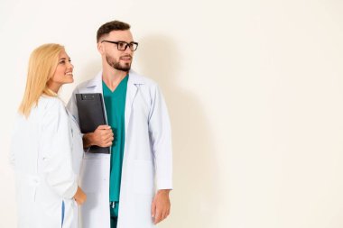 Kendine güvenen cerrahi doktor belge Pano duran başka bir doktor ile beyaz arka plan üzerinde tutar. Tıbbi hizmet ve sağlık insanlar kavramı.