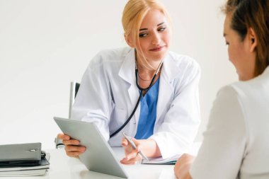 Kadın doktor konuşuyor ve Bayan hasta hastane ofisinde inceleyerek. Sağlık ve tıbbi hizmet.