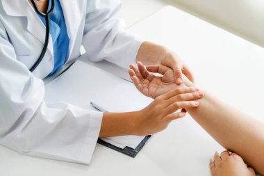 Kadın doktor hastane ofiste bayan hasta için eller tarafından hasta darbe incelenirken konuşuyor. Sağlık ve tıbbi hizmet.
