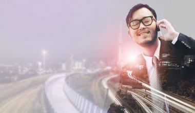 Genç işadamı istimal hareket eden telefon ile modern şehir binaları arka plan.