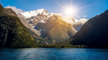 Göl ve dağ manzarası ile kar tepe yaz güneş mavi gökyüzü arka planda altında kepli. Atış Milford ses, Fiordland Milli Parkı, South Island, Yeni Zelanda.