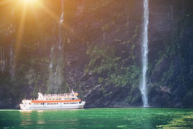 Gezi tekne turist kişi taşıyan büyük şelale Milford ses yaklaşıyor. Güzel manzara seyir ile Fiordland Milli Parkı içinde South Island, Yeni Zelanda.