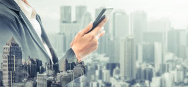 Cep telefonu ile modern şehir binaları arka plan kullanarak genç iş kadını. Gelecekteki telekomünikasyon teknolojisi ve internet şeyler (çok) kavramının.