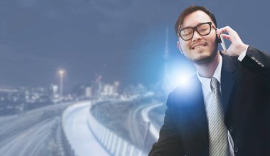 Genç işadamı istimal hareket eden telefon ile modern şehir binaları arka plan.