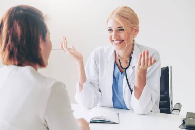 Kadın doktor konuşuyor ve Bayan hasta hastane ofisinde inceleyerek. Sağlık ve tıbbi hizmet.