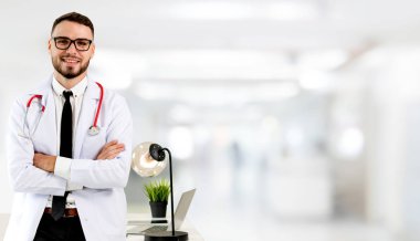 Yakışıklı doktor hastane ofiste ayakta ve kameraya bakıyor. Tıbbi doktor ve sağlık personeli hizmet.
