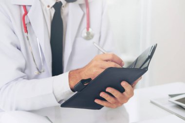 Doktor ofisinde hastanede bir kitap üzerine not yazarken okuma. Tıbbi ve sağlık kavramı.