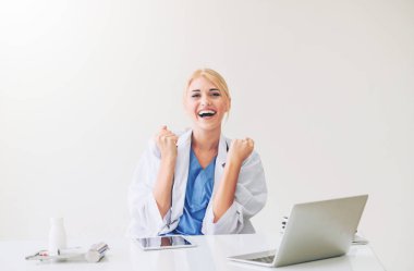 Mutlu başarılı kadın doktor hastane veya Sağlık Enstitüsü hoş ofis masası, tıbbi rapor üzerinde çalışırken düşünüyor. Başarı kavramı.