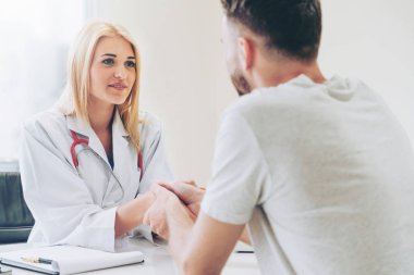 Kadın doktor hastane office odasında erkek hasta ile karşılıklı yapıyor. Sağlık ve Medikal hizmet meslekleri.