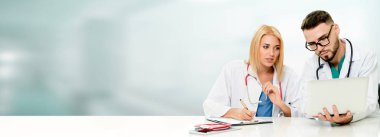 Doktor hastanede başka bir doktor ile bir tartışma yaparken ofiste dizüstü bilgisayarla çalışma. Tıbbi sağlık ve doktor hizmeti.