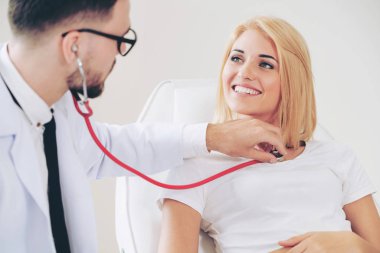 Erkek doktor konuşuyor ve Bayan hasta hastane ofisinde inceleyerek. Sağlık ve tıbbi hizmet.