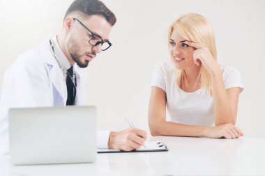 Hastanın sağlık kaydının tablosundaki tarih yazarken hastane ofiste bayan hasta için erkek doktor konuşuyor. Sağlık ve tıbbi hizmet.