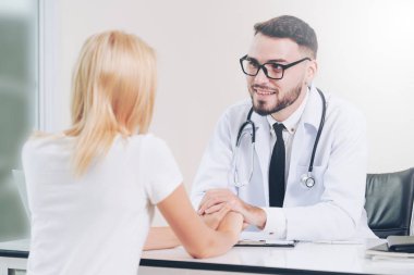 Erkek doktor hastane ofiste bayan hasta hasta ellerini tutarak yatıştırır. Sağlık ve tıbbi hizmet.